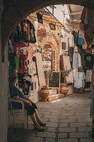 Old lady shaded for cool at a tourist shop