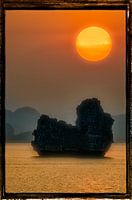 A large sun setting behind a large cliff.