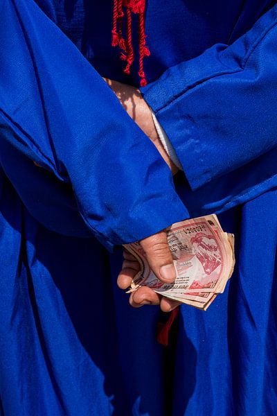 Detail of hand with money, bright blue traditional dress by Astrid van der Zijden