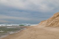 Vagues à tête d'écume, sable de plage doré à la dérive, sur la côte atlantique près d'Obidos, au Portugal.