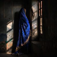 Frau in blauem Sari starrt verträumt nach draußen