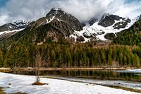 A frozen lake in the Alps with heavy clouds hanging over the mountains