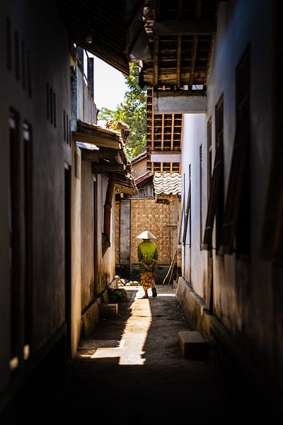 Une vieille dame se promène dans le village dans des vêtements traditionnels en batik indonésien. par Jeroen Cox