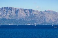 Blue seascape with sailboats and mountains in the background