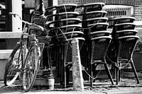 Fahrrad gegen Stange mit gestapelten Stühlen