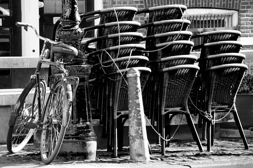 Fahrrad gegen Stange mit gestapelten Stühlen von Marion Hesseling
