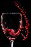 Rotwein spritzte in und neben dem Glas