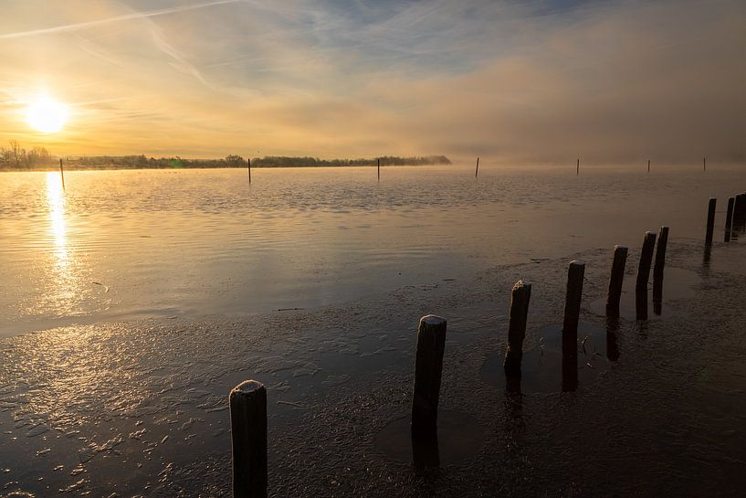 misty sunrise over the water with reflective poles and pastel colors by Kim Willems