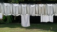 The white laundry hangs to dry in beautiful backlight at a farm