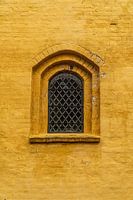 Kirchenfenster in ockerfarbener Wand.