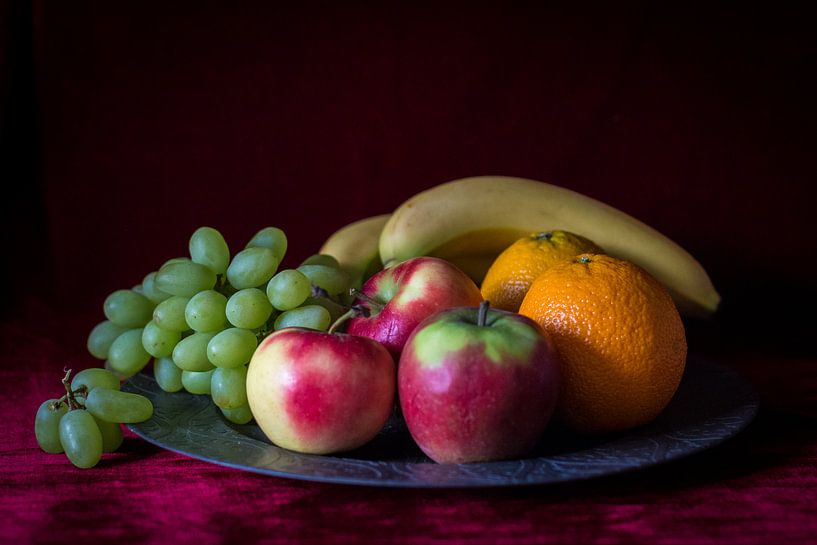 Stilleven van fruitschaal met vers fruit op warm rode achtergrond von Piertje Kruithof