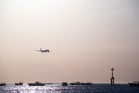 Landend vliegtuig boven zee tijdens zonsondergang