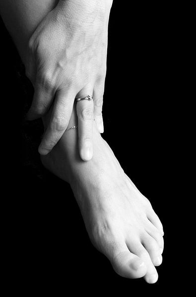 hand van een vrouw ligt op haar voet von Anita Hermans