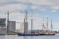 Klassieke twee- en driemaster varen langs de woningen in aanbouw bij de Houthavens in Amsterdam bij 
