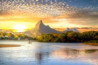 La baie de Tamarin sur l'île Maurice au coucher du soleil avec une chaîne de montagnes et des pagaye