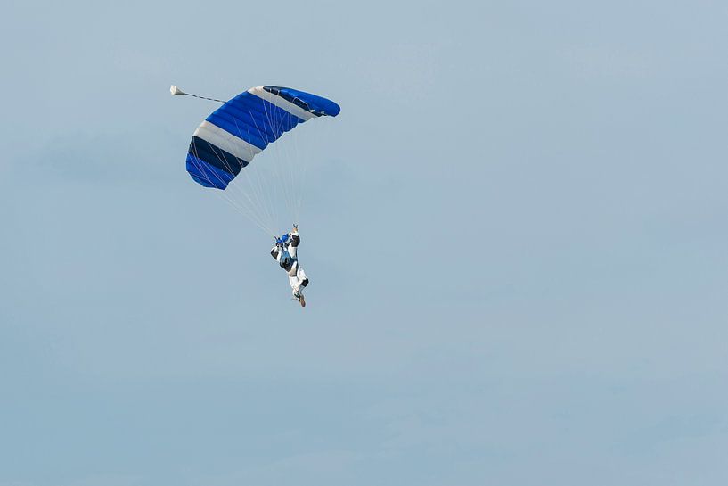 Parachutist aan een blauwe parachute tegen een licht blauwe achtergrond par Tonko Oosterink