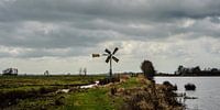Polderlandschap met dijk, windmolen en waterpartij