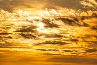 Sonne hinter Wolken an einem goldenen Himmel