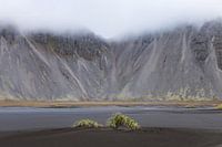 plage de lave désolée avec des nuages ​​autour des montagnes