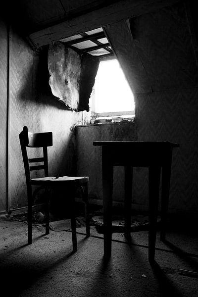 Table and chair in a room in an abandoned house by Jacqueline Groot