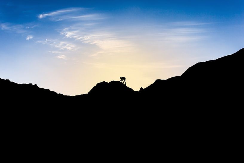 Silhouette of man climbing mountain at sunset. Wout Kok One2expose by Wout Kok