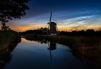 Lichtende nachtwolken boven een windmolen in de polder