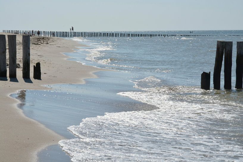 Beach with surf and poles in the sea by Trinet Uzun