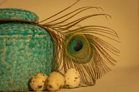 Aquablaue Vase mit warmen Pfauenfedern im Hintergrund