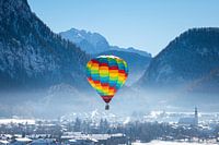 Hot air balloons adorn the sky over a snowy Inzell in Germany