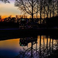 Beleuchteter LKW spiegelt sich im Wasser des Flusses Linge