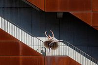 A pose of a ballet dancer on the stairs of a building