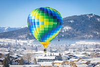 Hot air balloons adorn the sky over a snowy Inzell in Germany