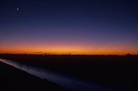 Paysage d'hiver avec la lune au coucher du soleil.