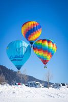 Hot air balloons adorn the sky over a snowy Inzell in Germany