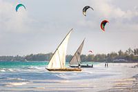 Alte traditionelle Segelboote am Strand von Sansibar mit Kite-Surfern im Hintergrund
