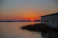 Sunset over the lake in the summer with wooden houses on the shore