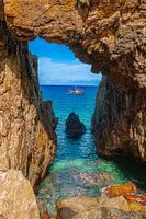 Vietnamese fishing boat sails past a cave opening