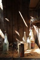 Flessenpost- stilleven met flessen in verlaten oud huis