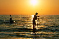 Ondergaande zon - Peddelen in de branding bij Zandvoort