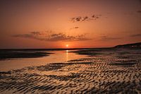 Setting sun colors everything red on the beach