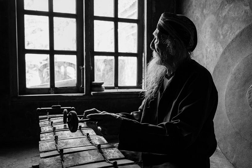 Un portrait en noir et blanc du maestro du gamelan Ki Suripto sur son gamelan à Salatiga, Java centr par Anges van der Logt