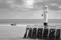 Light beacon along the coast in Blankenberge with a fishing boat