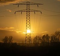 Silhouet van een hoogspanningsmast bij zonsondergang