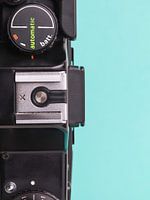 Close up of vintage 'Praktica' camera on blue/green background.