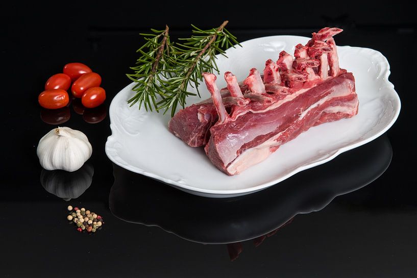 Plat blanc avec un carré d'agneau et quelques ingrédients d'accompagnement par Wim Stolwerk