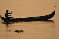 Indiër in kano bij ondergaande zon