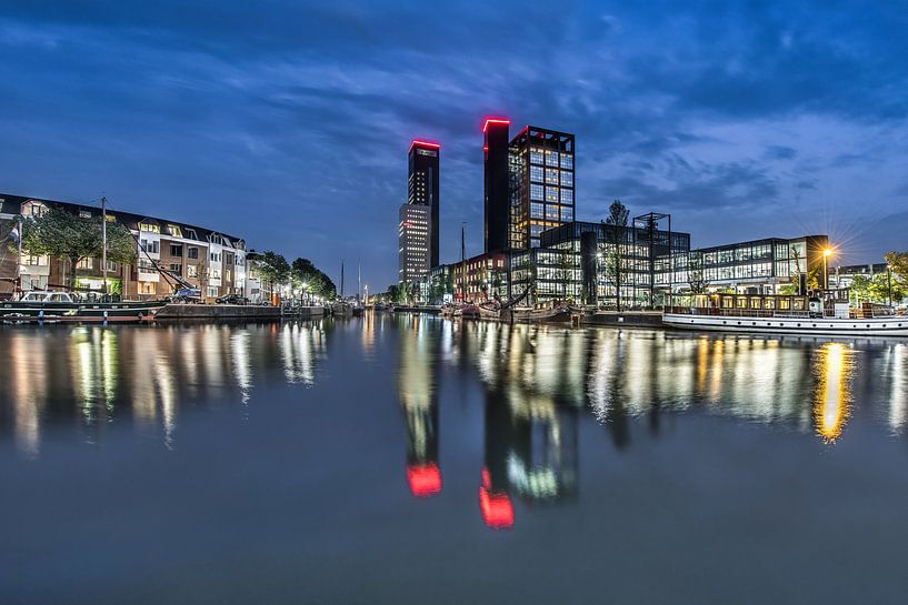 De skyline van Leeuwarden tijdens het blauwe uurtje en weerspiegeld in de stadsgracht. by Harrie Muis